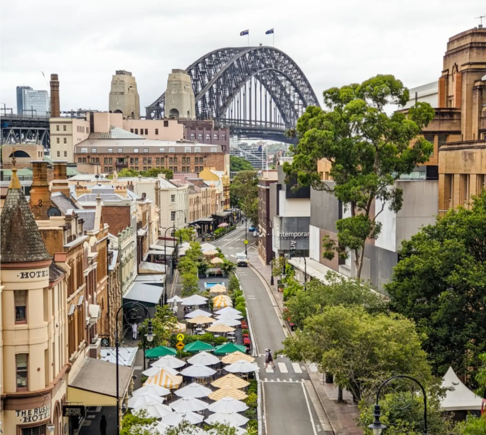 Historic sandstone and brick buildings of The Rocks with outdoor market umbrellas and the Sydney Harbour Bridge behind, part of the Sydney area serviced by Mould Hunters